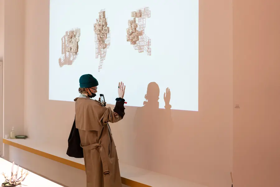 Visitor in front of a projection of ceramic forms