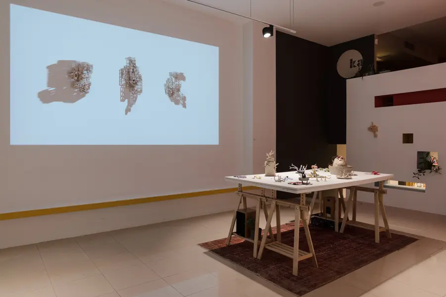 Exhibition room with a projection and a table of works