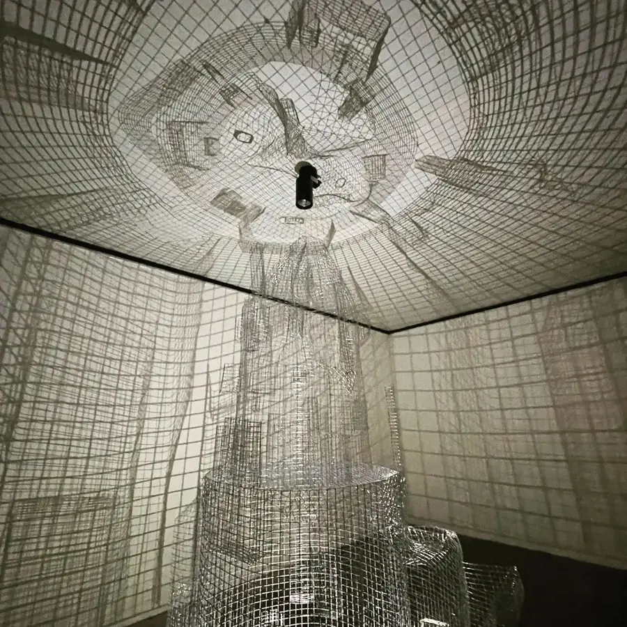 Room lined with grid patterns, a figure-like grid form at the centre