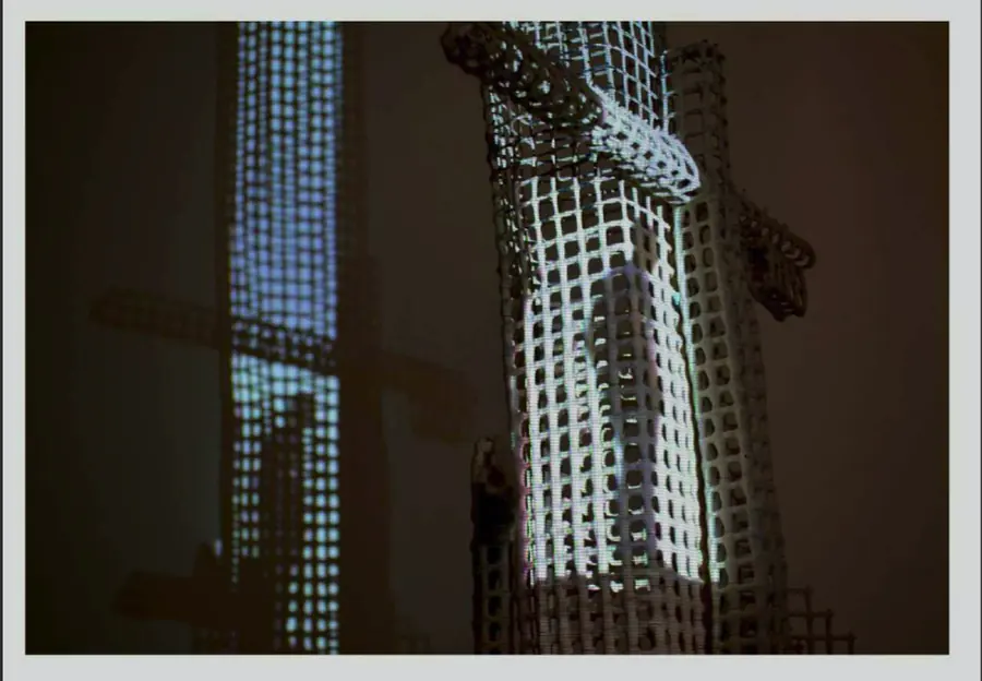 Grid tower lit by a video projection in a dark room