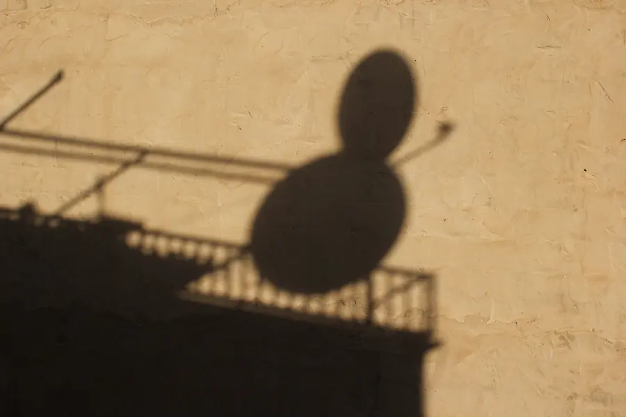 Shadow of a balcony and satellite dish on a warm-coloured wall